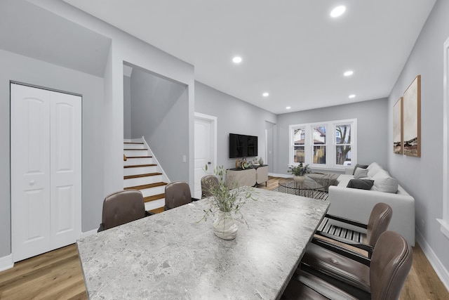 dining area with light wood-style floors, stairs, baseboards, and recessed lighting