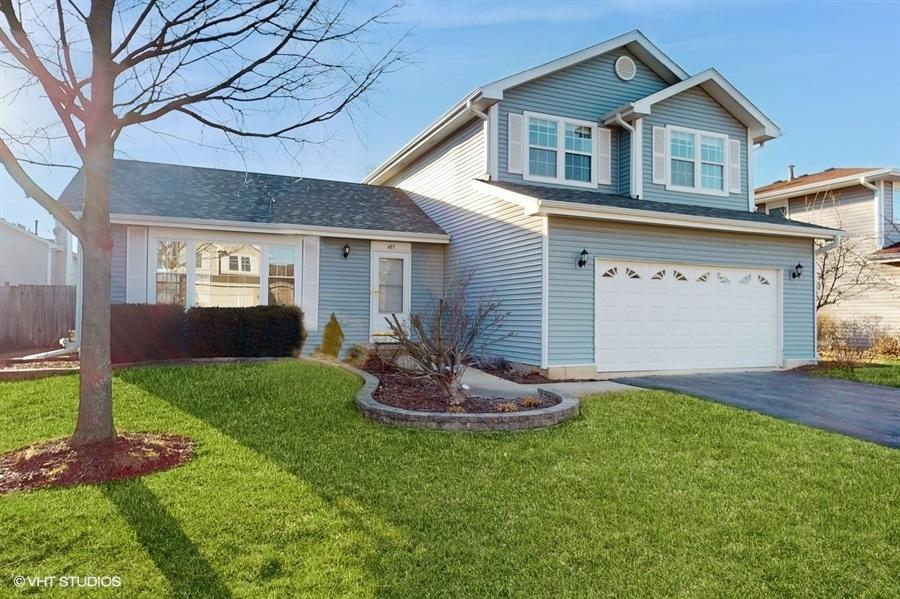 traditional-style home with aphalt driveway, an attached garage, fence, and a front lawn