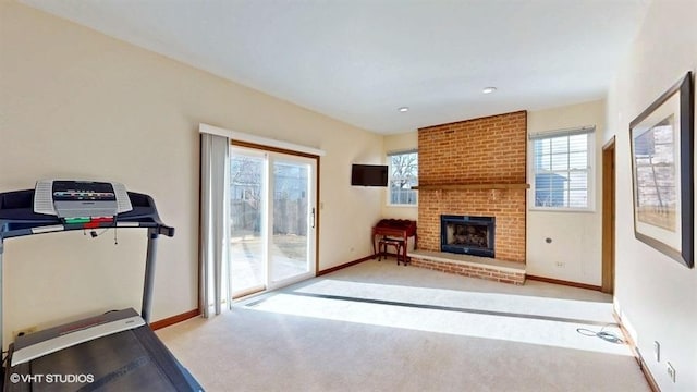 exercise room featuring baseboards, carpet, and a brick fireplace