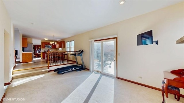 exercise area with light colored carpet, baseboards, and an inviting chandelier