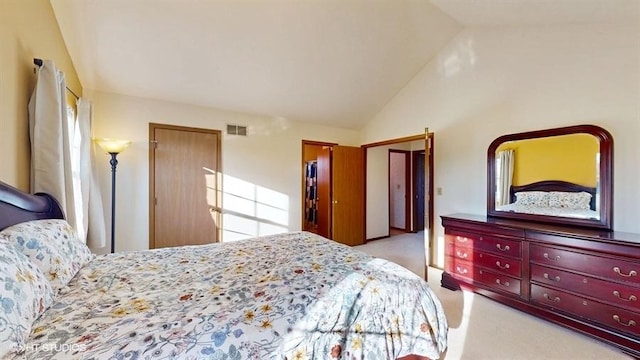 bedroom featuring vaulted ceiling, light colored carpet, and visible vents