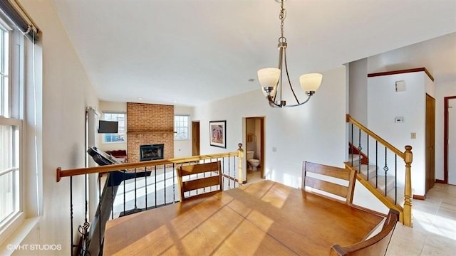 dining room with a notable chandelier, a brick fireplace, and stairway