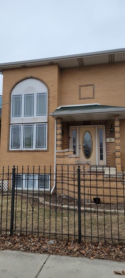 view of front of property with a porch, brick siding, and a fenced front yard