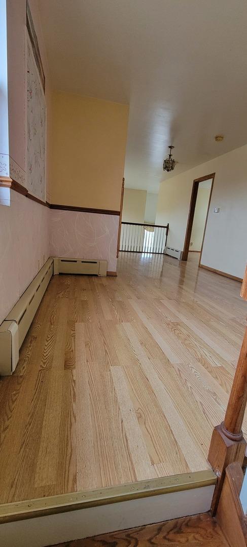 unfurnished room featuring wood finished floors and a baseboard radiator