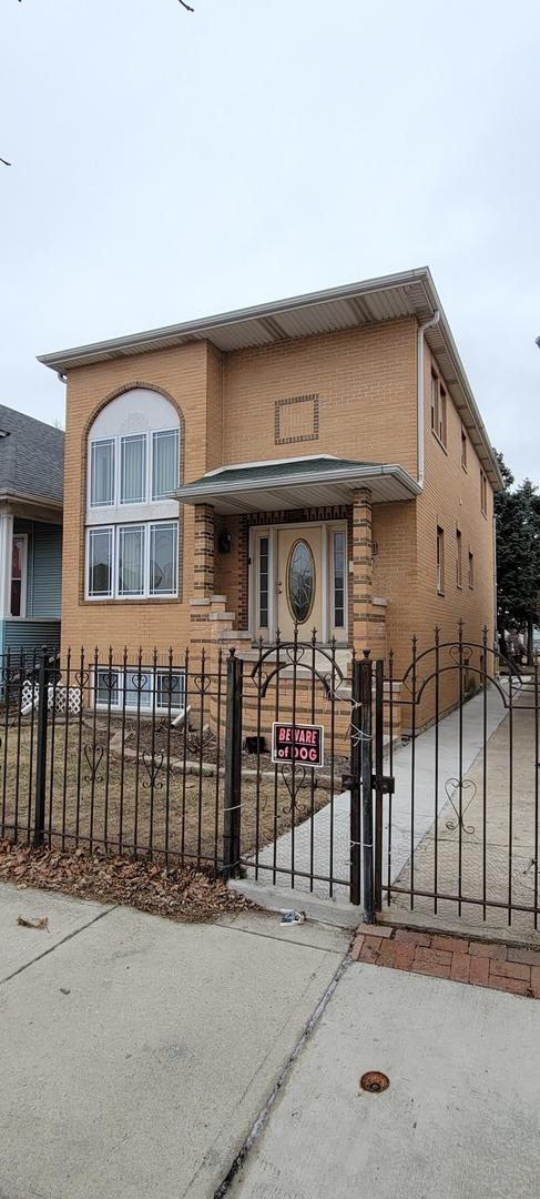 view of front of home featuring a fenced front yard, brick siding, and a gate