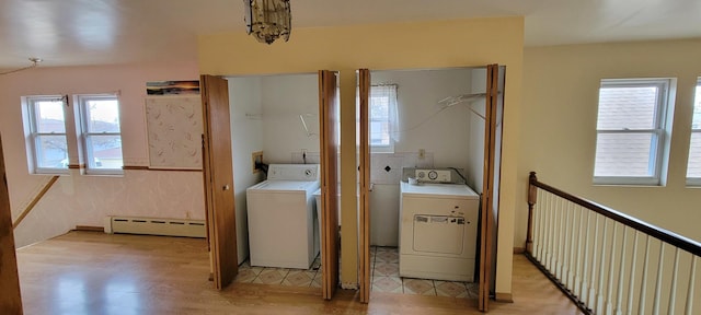 laundry room with a baseboard heating unit, a healthy amount of sunlight, light wood finished floors, and washing machine and clothes dryer