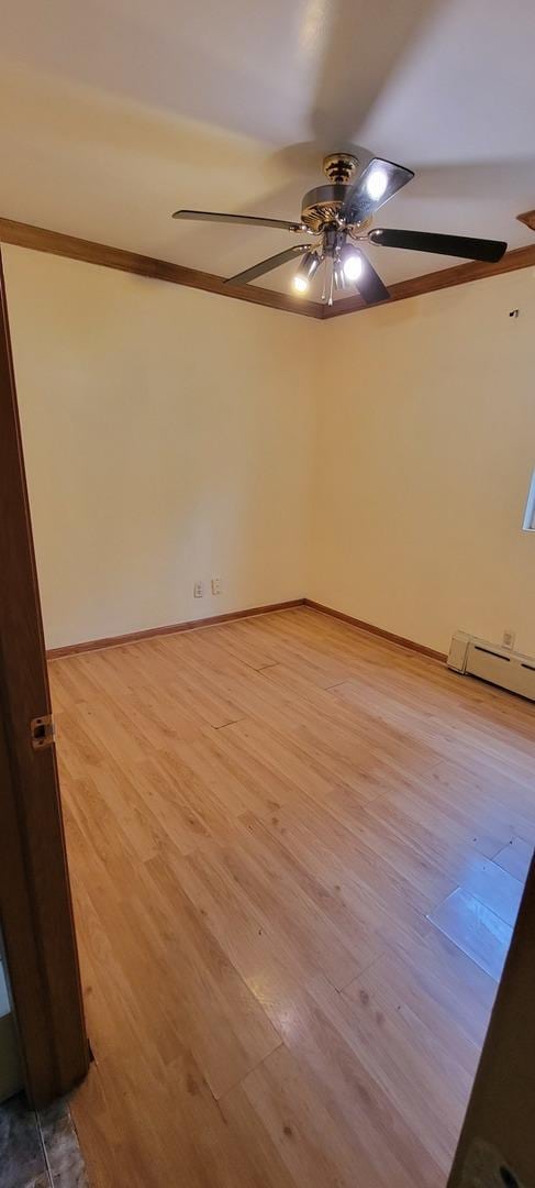 spare room with a baseboard heating unit, baseboards, light wood-style flooring, and a ceiling fan