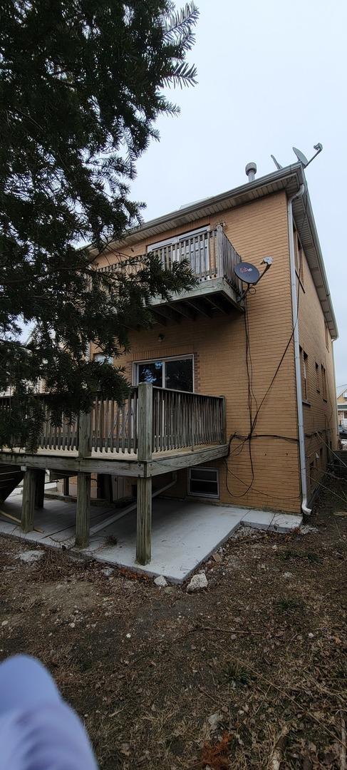 back of property featuring a patio, brick siding, and a balcony