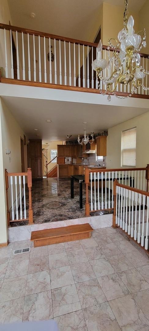 stairs with marble finish floor, a towering ceiling, and a chandelier