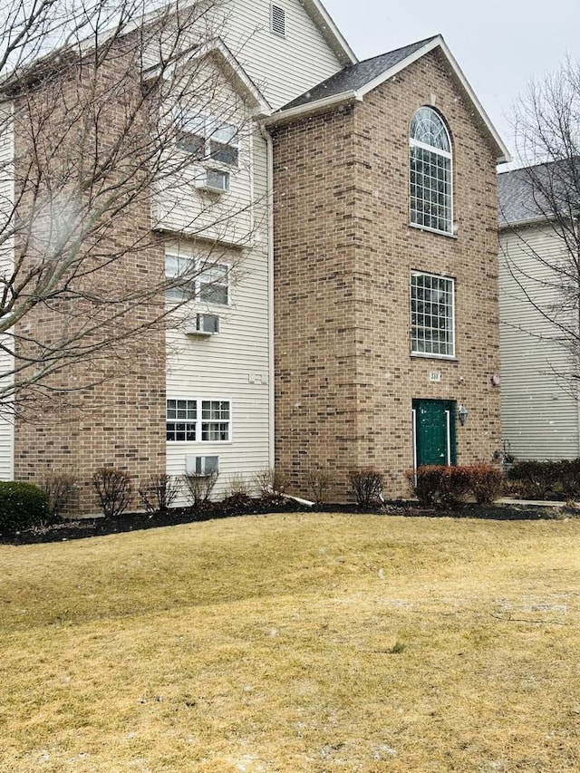 view of home's exterior with a yard, brick siding, and cooling unit