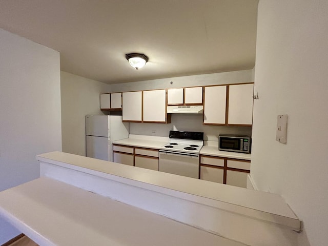 kitchen with white appliances, light countertops, under cabinet range hood, and white cabinets