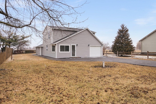 view of property exterior with aphalt driveway, a yard, fence, and a garage