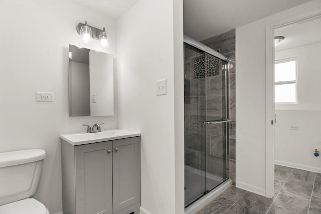 bathroom featuring vanity, a shower stall, toilet, and baseboards