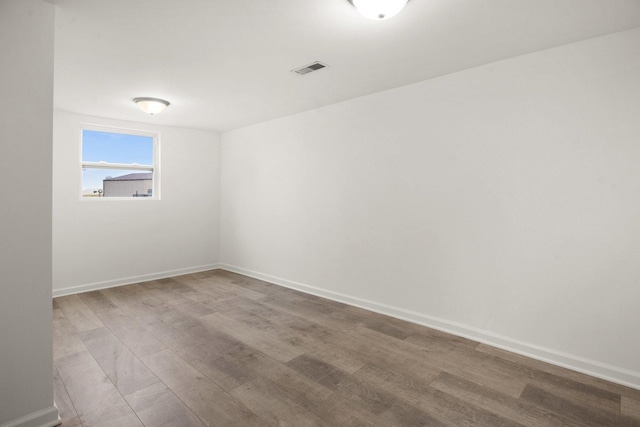 spare room with visible vents, baseboards, and wood finished floors