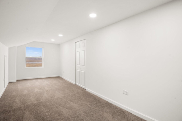 carpeted empty room featuring recessed lighting, lofted ceiling, and baseboards