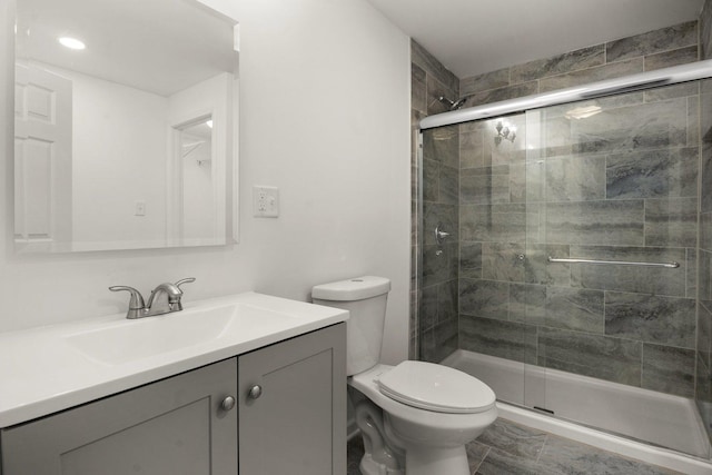 full bathroom featuring a shower stall, toilet, and vanity