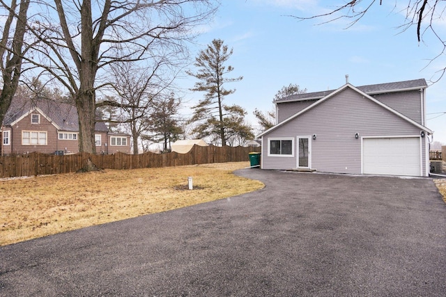 exterior space featuring aphalt driveway, an attached garage, and fence