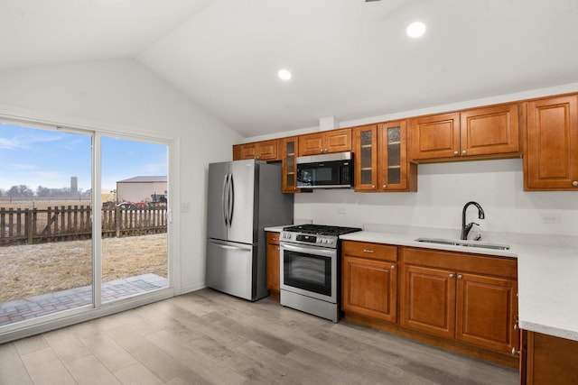 kitchen featuring brown cabinetry, stainless steel appliances, light countertops, and a sink