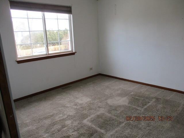 carpeted spare room featuring baseboards