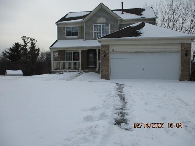 view of front of home with a garage, covered porch, and brick siding