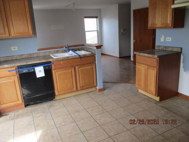 kitchen featuring black dishwasher, a sink, a peninsula, and light tile patterned floors