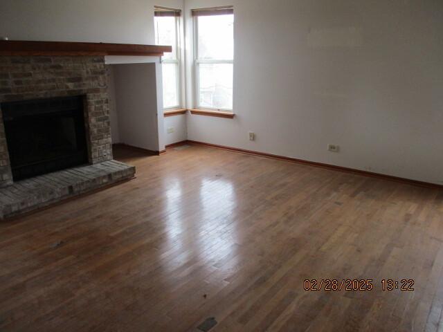 unfurnished living room featuring a fireplace, wood finished floors, and baseboards