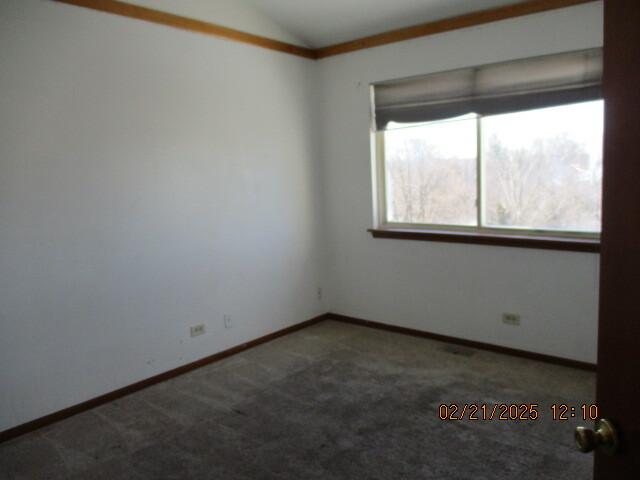 carpeted empty room featuring lofted ceiling and baseboards