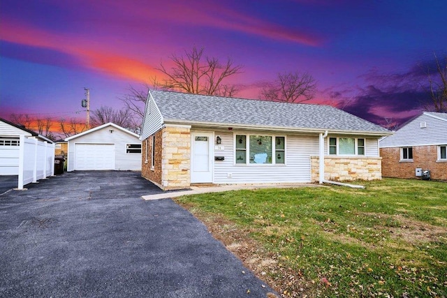 ranch-style house featuring stone siding, a detached garage, aphalt driveway, an outbuilding, and a yard