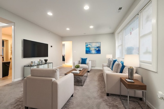 carpeted living room featuring baseboards, visible vents, and recessed lighting