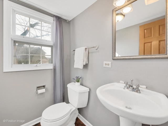 bathroom with toilet, baseboards, and a sink