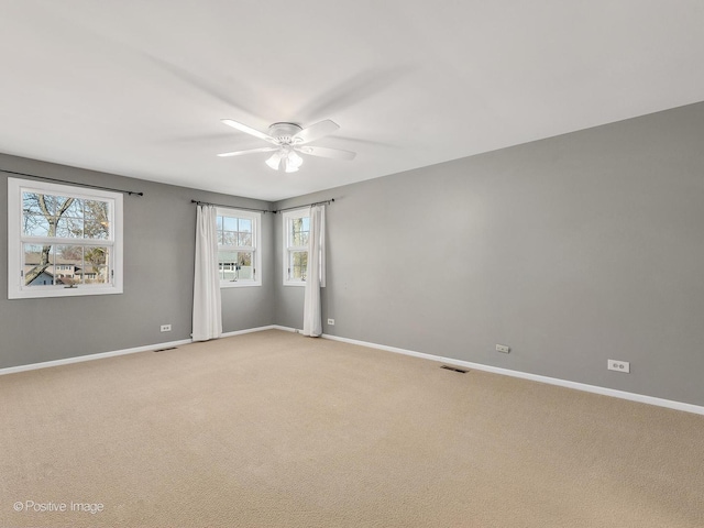 spare room with visible vents, baseboards, light colored carpet, and ceiling fan