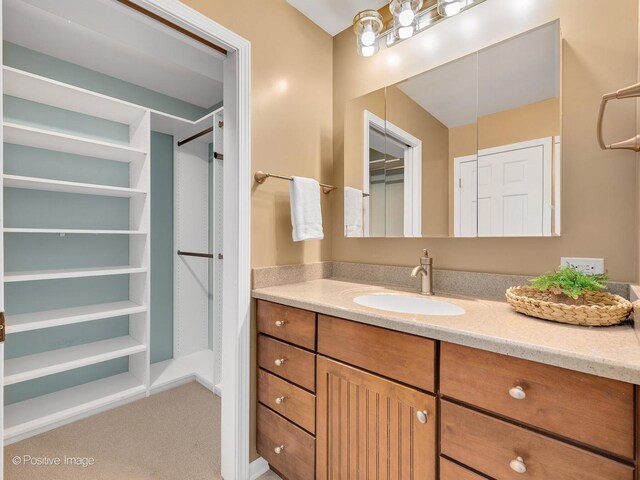 bathroom with a walk in closet and vanity