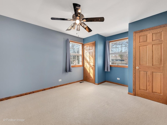 unfurnished bedroom featuring carpet flooring, multiple windows, visible vents, and baseboards