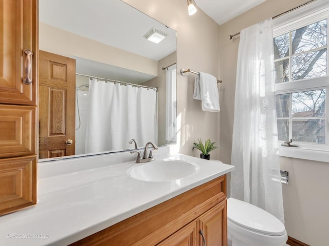 bathroom featuring vanity, toilet, and visible vents