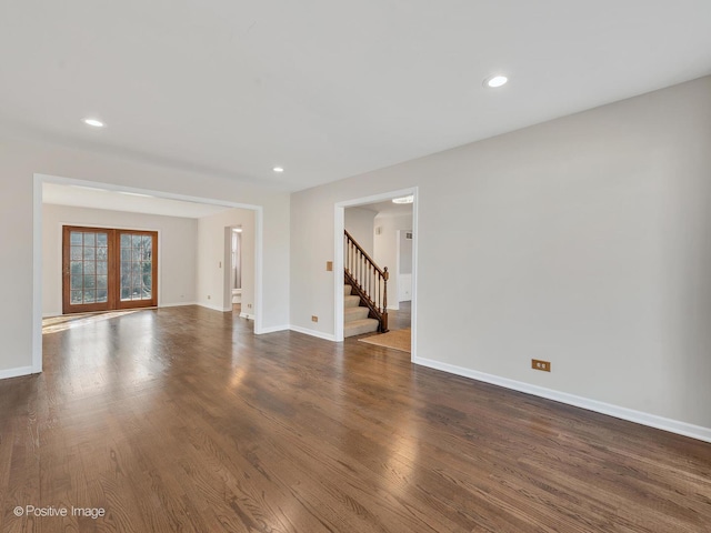 unfurnished living room featuring stairs, dark wood finished floors, baseboards, and french doors