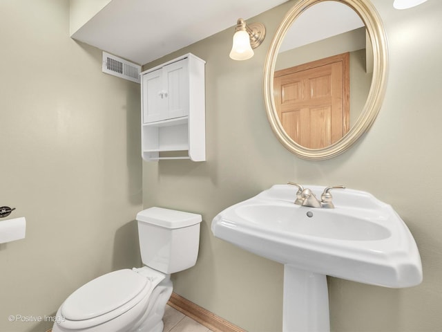 half bathroom featuring visible vents, toilet, a sink, tile patterned flooring, and baseboards