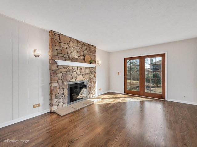 unfurnished living room featuring a fireplace, baseboards, and wood finished floors