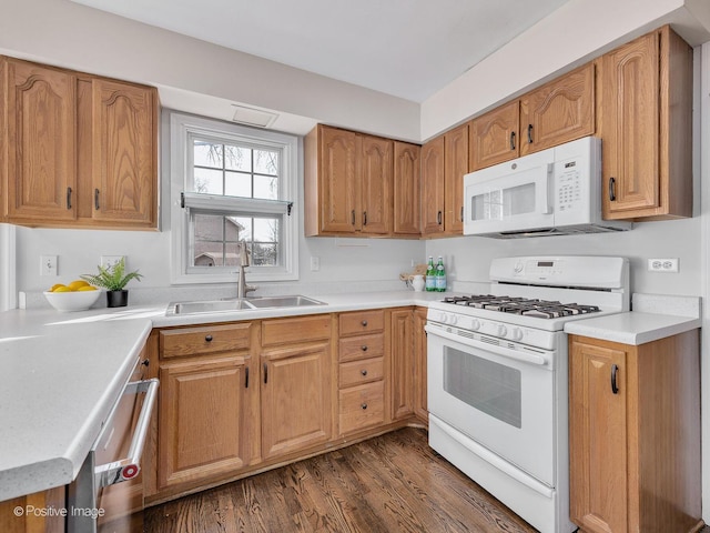 kitchen with dark wood-type flooring, light countertops, brown cabinets, white appliances, and a sink