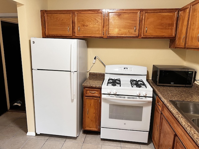 kitchen featuring dark countertops, white appliances, and brown cabinetry