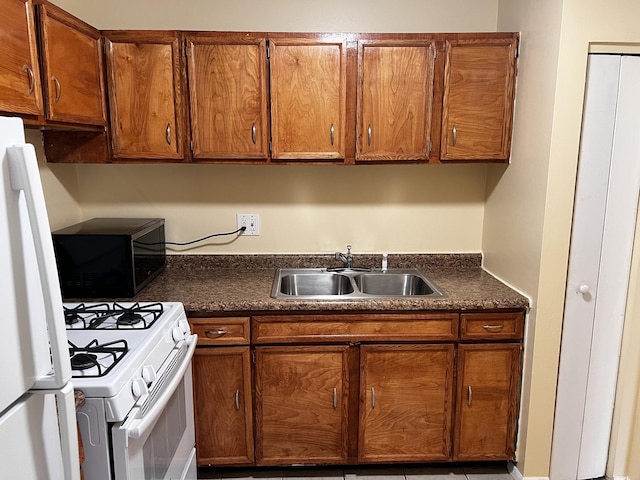 kitchen featuring dark countertops, white appliances, brown cabinetry, and a sink