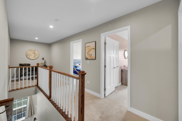 hall with recessed lighting, baseboards, light colored carpet, and an upstairs landing