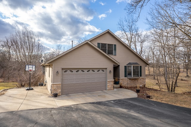 view of front of property featuring a garage, stone siding, and driveway