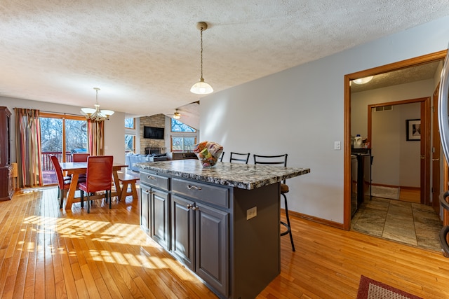 kitchen with light wood-style flooring, a fireplace, a breakfast bar, and a wealth of natural light