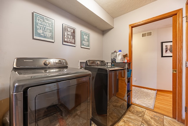 laundry room with a textured ceiling, laundry area, visible vents, baseboards, and independent washer and dryer