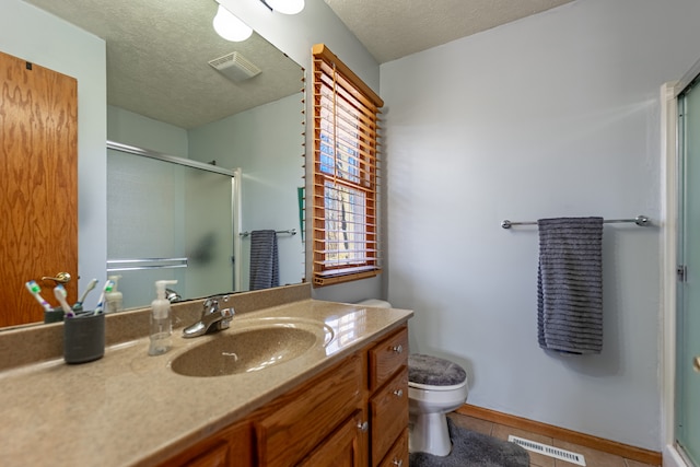 bathroom featuring a shower with shower door, visible vents, and a textured ceiling