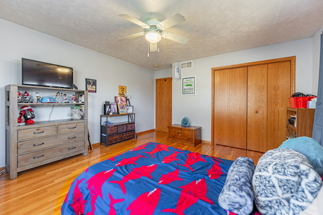 bedroom featuring a closet, visible vents, light wood-style floors, ceiling fan, and a textured ceiling