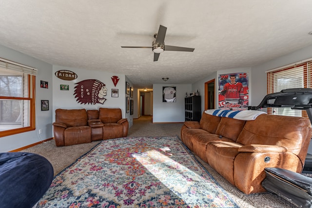 carpeted living area with a ceiling fan, baseboards, and a textured ceiling