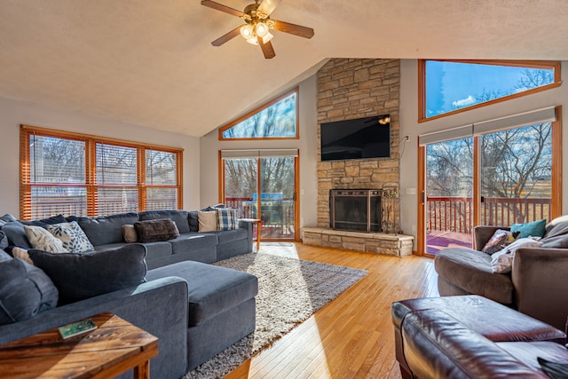 living area with hardwood / wood-style flooring, ceiling fan, a fireplace, and high vaulted ceiling