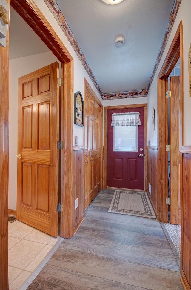 entryway featuring wood finished floors, wainscoting, and wood walls