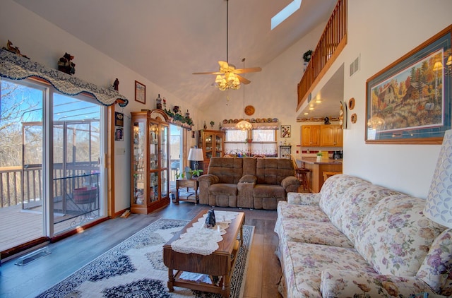 living area featuring wood finished floors, ceiling fan, high vaulted ceiling, and a skylight